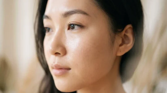 Gros plan sur une peau lumineuse et translucide évoquant l'effet 'glass skin', avec un éclairage doux et naturel
