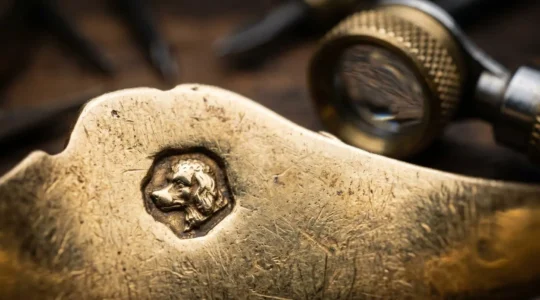 Macro photographie d'un poinçon tête d'aigle gravé sur un bijou ancien en or, loupe de bijoutier et patine naturelle du métal